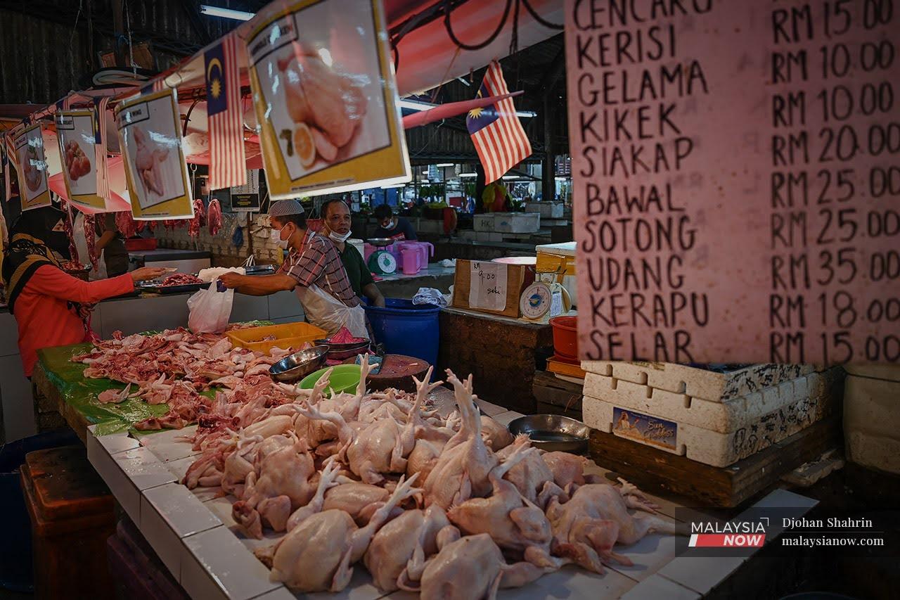 A customer pays a chicken vendor at his stall at the Datuk Keramat wet market in Kuala Lumpur.