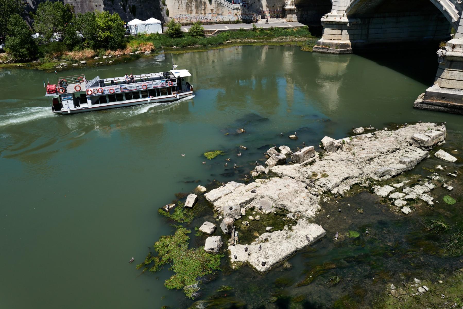 This picture taken on July 2 in Rome shows a tourist river boat sailing near the Vittorio Emanuele II bridge, as the low water level of the river Tiber reveals an ancient bridge built under Roman Emperor Nero. Photo: AFP