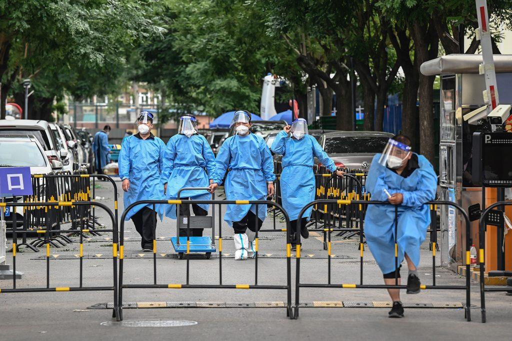 Workers and security guards in protective gear are seen at a cordoned-off entrance to a residential area under lockdown due to Covid-19 restrictions in Beijing on June 14. Photo: AFP