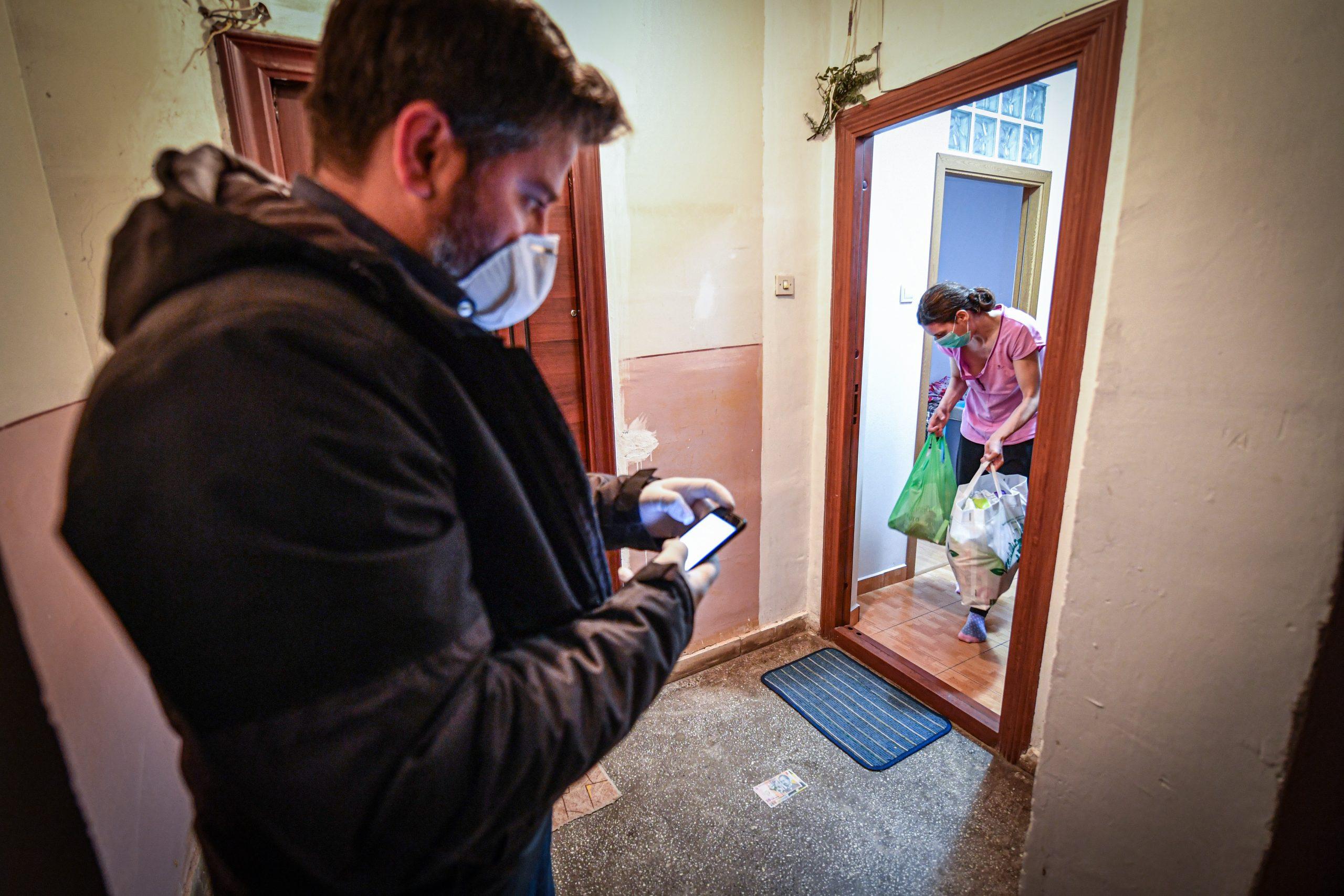 A man checks his phone for new calls for help, as he delivers shopping to a young mother who stays confined at her home due to the novel coronavirus epidemic on March 15, 2020 in Bucharest. Photo: AFP