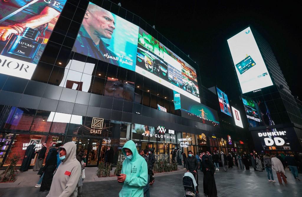People walk beneath advertisement billboards at Boulevard entertainment city in the Saudi capital Riyadh, late on Jan 19. Photo: AFP