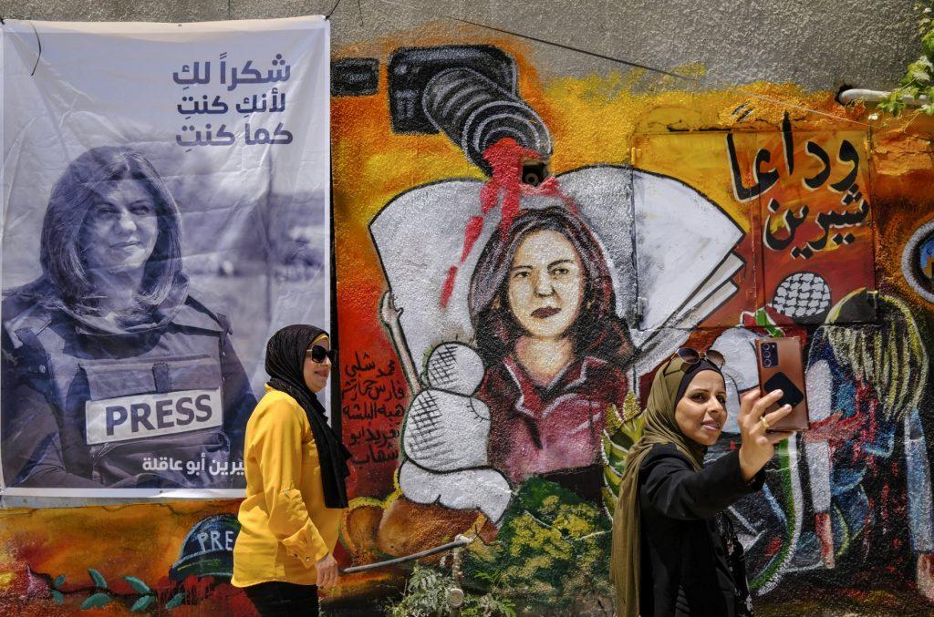 Palestinian women stand in front of a mural, part of an art exhibit honouring slain Al-Jazeera journalist Shireen Abu Akleh at the spot where she was killed on May 11 while covering an Israeli army raid in Jenin in the occupied West Bank. Photo: AFP
